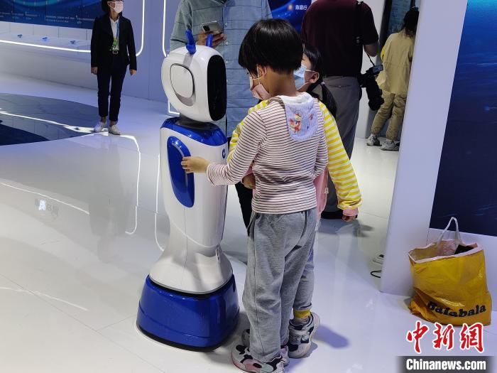 图为：小朋友和机器人聊天。　叶秋云 摄